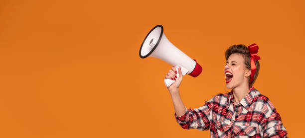 istock Smiling happy pinup woman screaming through megaphone. 1311082196