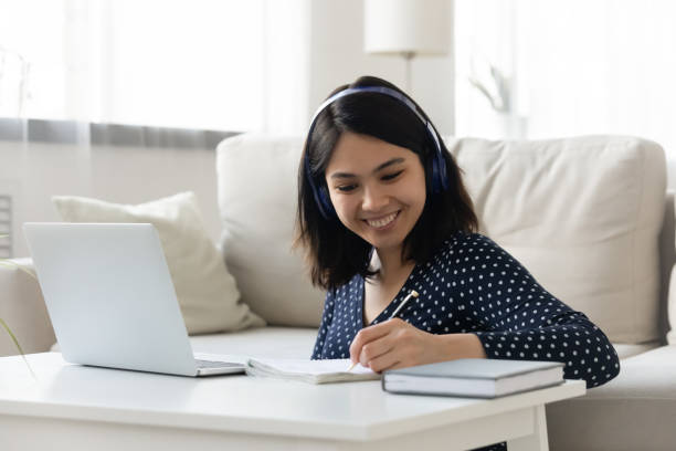 istock Asian woman in headset sit before pc write in copybook 1311084144