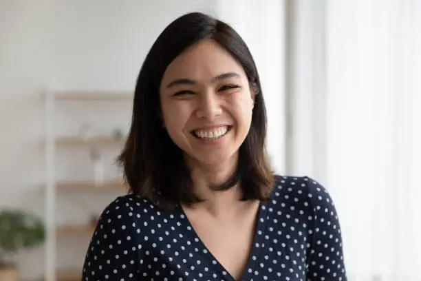 Portrait of happy overjoyed pretty asian woman look at camera with sincere laughter. Laughing excited female customer leave positive video feedback to ordered goods received service on company website