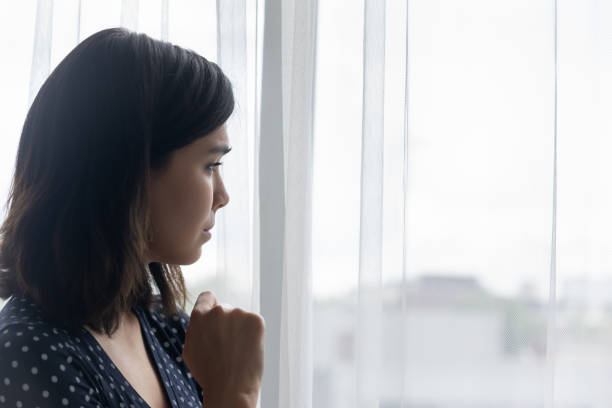 ansioso triste jovem asiático chorando sozinho olhando para a janela - mental health relationship difficulties teenager divorce - fotografias e filmes do acervo