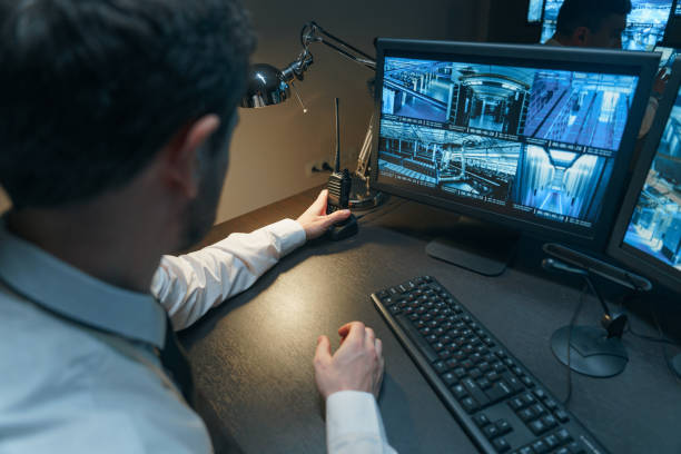 The security officer is at his desk, reaching for his walkie-talkie to answer the incoming signal. The security officer will transmit the information to his workmates via walkie-talkie communication that everything is in order. el oficial de seguridad está en su escritorio, buscando a su walkie-talkie para responder a la señal entrante. el oficial de seguridad transmitirá la información a sus compañeros de trabajo a través de la comunicación walkie-talkie de que todo está