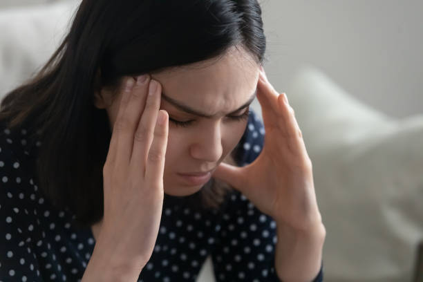 istock Young asian female sit alone rub temples having headache migraine 1311084717