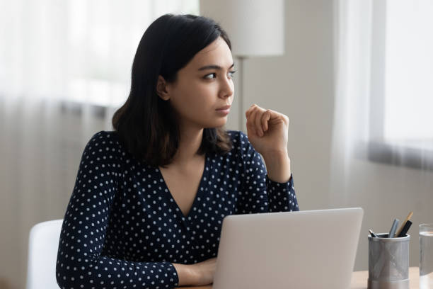 istock Thoughtful vietnamese female look aside of laptop visualize work result 1311084743