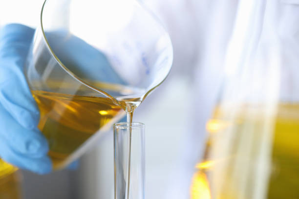 istock Scientist chemist pouring oil from flask into glass closeup 1311084883