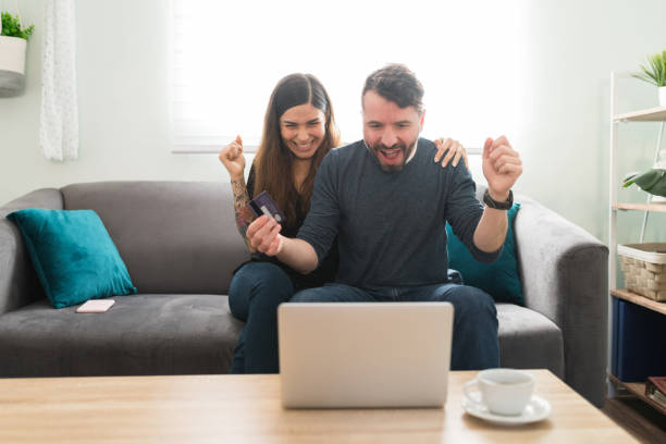 petit ami et petite amie se sentant excités au sujet de leurs achats en ligne - women computer couple surprise photos et images de collection