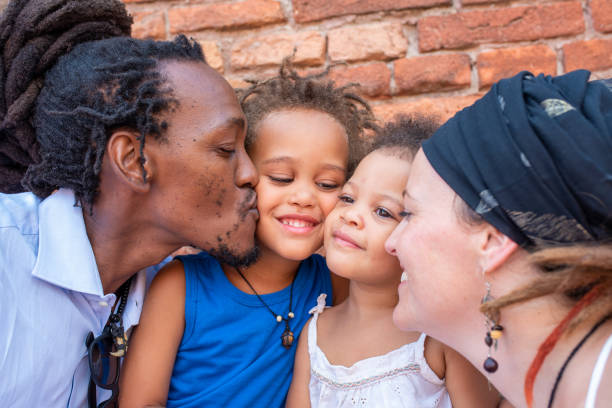 moments d’amour et de douceur d’une famille mixte afro-caucasienne, les parents rastafaniens embrassent leur fils et leur fille - couple black american culture kissing photos et images de collection