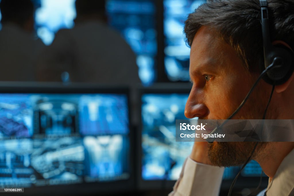 Close-up of the face of a male security guard, security service, police officer, rescue service, who is negotiating with a wireless headset. Police Force Stock Photo