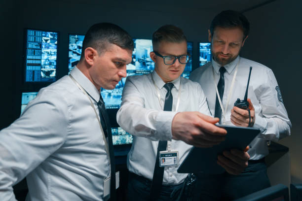 A group of security guards study the new instructions on a digital tablet. stock photo