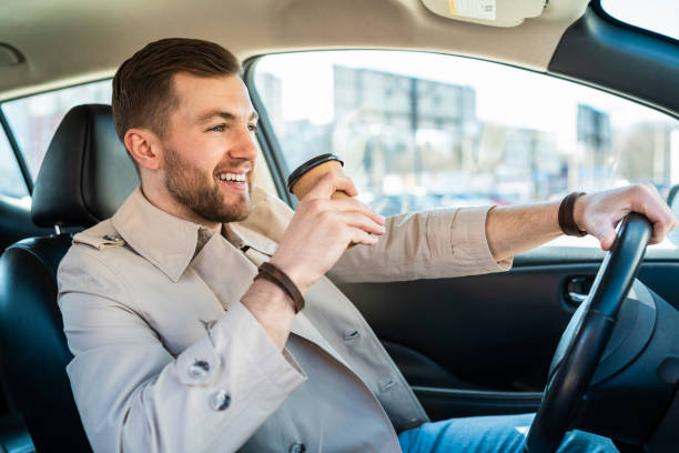 istock Handsome man with cup of coffee driving car 1311086644
