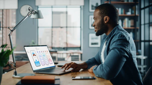 istock Handsome African American Designer Working on Desktop Computer in Creative Living Room. Freelance Male is Developing New Food Delivery App Design, User interface in a Digital Graphics Editing Software 1311088171