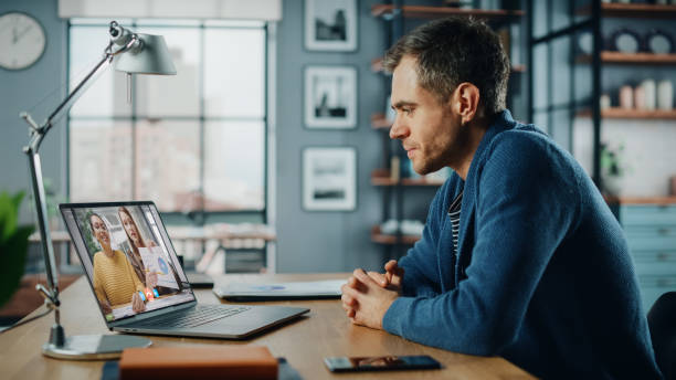 istock Handsome Caucasian Man Having a Video Call on Laptop Computer while Sitting Behind Desk in Living Room. Freelancer Working From Home and Talking to Colleagues and Clients Over the Internet. 1311088292