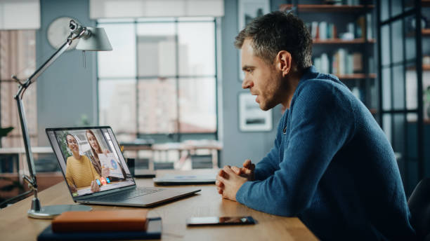 istock Handsome Caucasian Man Having a Video Call on Laptop Computer while Sitting Behind Desk in Living Room. Freelancer Working From Home and Talking to Colleagues and Clients Over the Internet. 1311088314