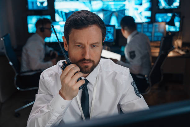 Portrait of a man who urgently transmits information using his walkie-talkie. Portrait of a man who urgently transmits information using his walkie-talkie. In real time, the security post receives urgent information. It is very important to communicate the received information using the walkie-talkie very quickly. The man is as serious and focused as possible. emergency control center stock pictures, royalty-free photos & images