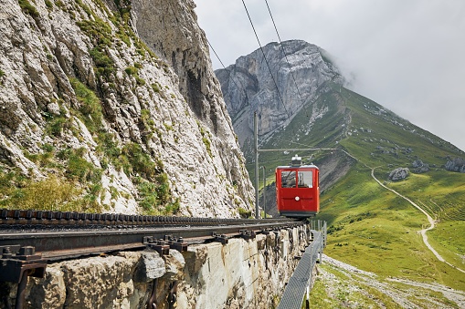 Cogwheel train passing mountain landscape of Swiss Alps.Red train on cog railway between Mount Pilatus and Alpnachstad near Lucerne.