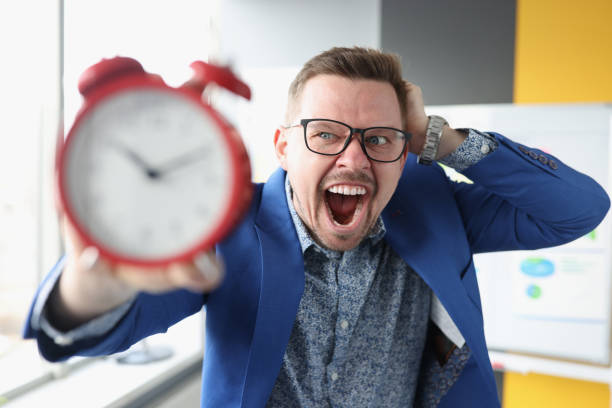 Businessman in glasses holding red alarm clock in his hands and shouting Businessman in glasses holding red alarm clock in his hands and shouting. Business time management concept speed o stock pictures, royalty-free photos & images