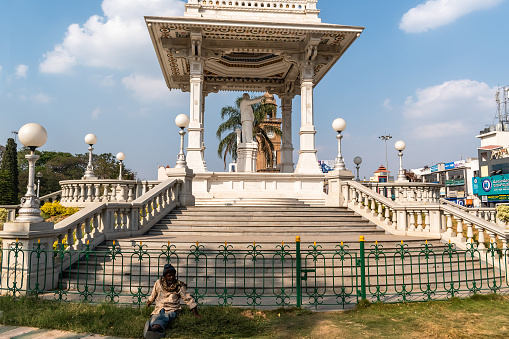 Mysuru, Karnataka, India - January 2019: An Indian man sitting in a park outside a statue of Dr. Babasaheb Ambedkar in the city of Mysore.