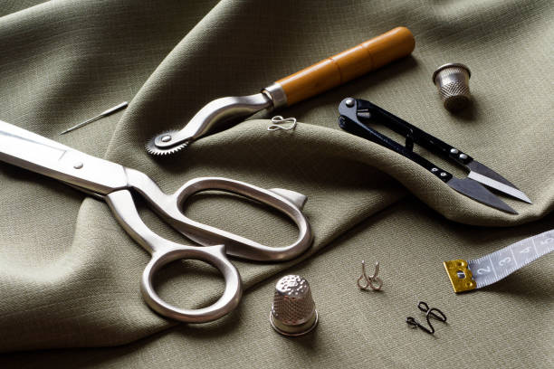 istock Sewing supplies lie on draped fabric, close-up. Sewing background. Spools of thread, a centimeter, scissors, a thimble, on a gray draped cloth. Atelier concept. Fashion designer. Sewing composition 1311096124