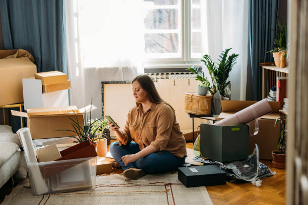 istock Moving In: Young Beautiful Plus Size Woman Sitting on the Floor while Using a Smartphone (Horizontal) 1311096900