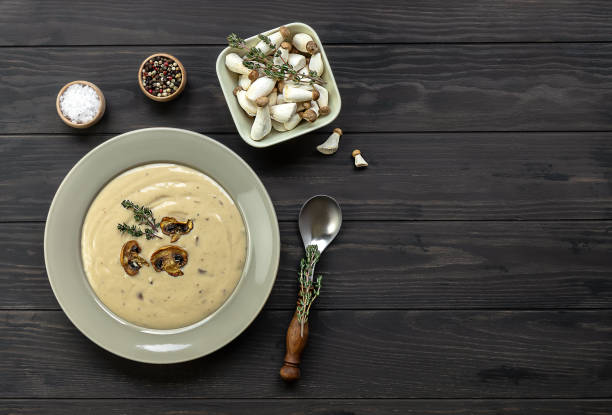 Delicious mushroom cream soup with thymes on the wooden table. Horizontal top view from above Delicious mushroom cream soup with thymes on the wooden table. Horizontal top view from above, copy space Cepe stock pictures, royalty-free photos & images