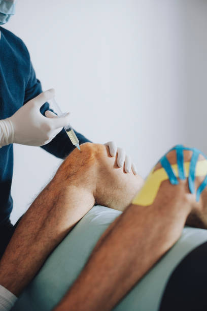 istock Doctor is Taking Out Knee Fluid from Patient's Knee with a Syringe 1311098214