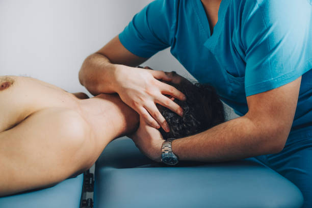 Doctor Physiotherapist Doing Neck Adjustment Patient is calmly lying on his back while the chiropractor is holding his neck, massaging it and adjusting it. chiropractor stock pictures, royalty-free photos & images