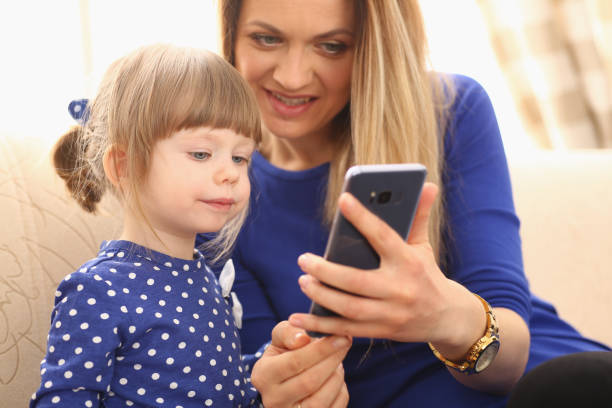 istock Cute little girl with smiling mom using smartphone 1311099101