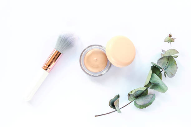 istock Concealer, make-up brush and green eucalyptus branch on white background. Top view 1311101456