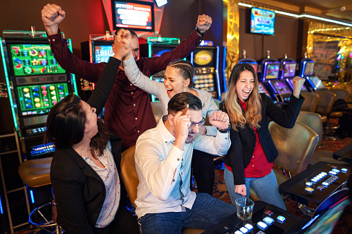 Happy group of friends winning while playing on slot machines
