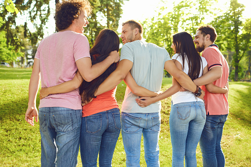 Young people hug in the park in nature. Back view.