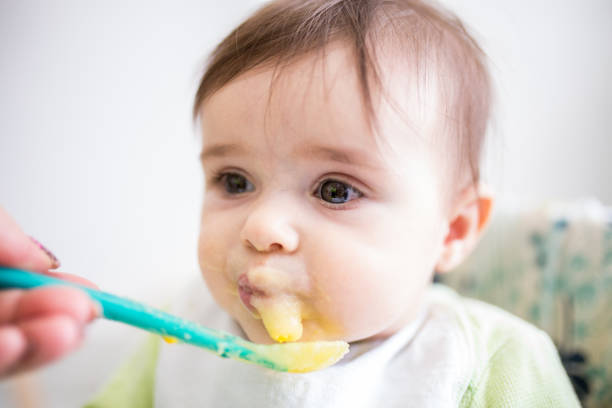 istock Mom feeds her beautiful baby with a spoon 1311104391