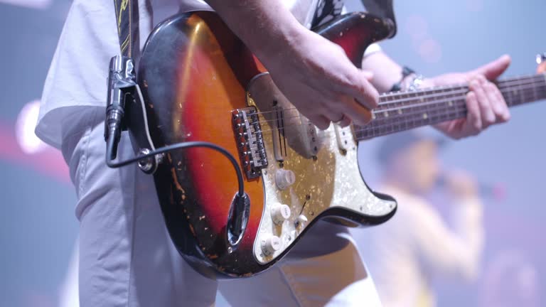 Guitarist plays rock music. Emotional expressive dynamic performance at a live concert. Bright stage light. Close-up