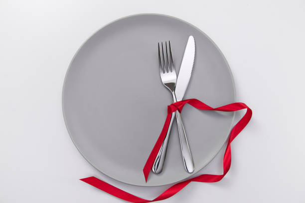 istock Festive table setting with red ribbon. Fork and knife on a gray plate and card postcard for text. Copy space. 1311107842