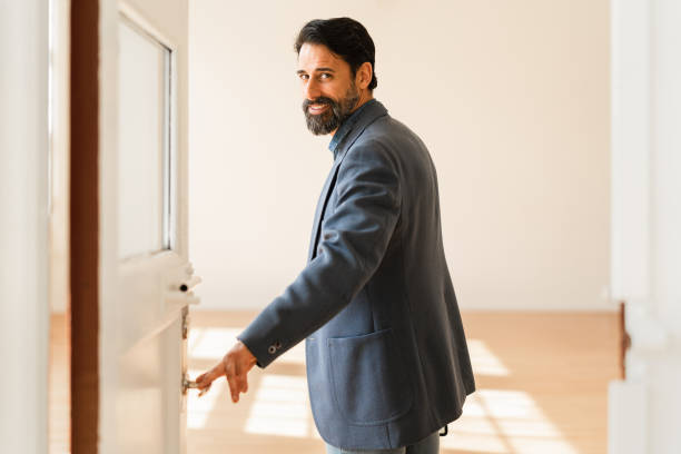 Businessman opening the doors to a new office space A businessman leading you in to his new office space. looking over shoulder stock pictures, royalty-free photos & images