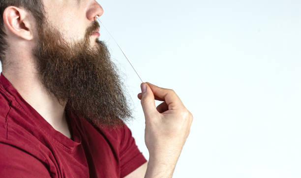 istock Coronavirus self test at home. young man performs a covid-19 quick test at home. test with cotton swab in the nose of the young man on white background, copy space 1311109698