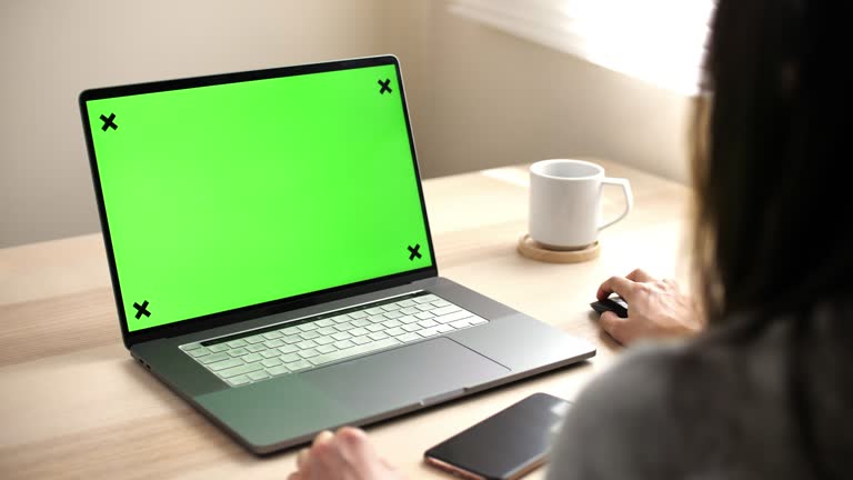 USA,Japan, Woman using Green screen laptop on desk at home