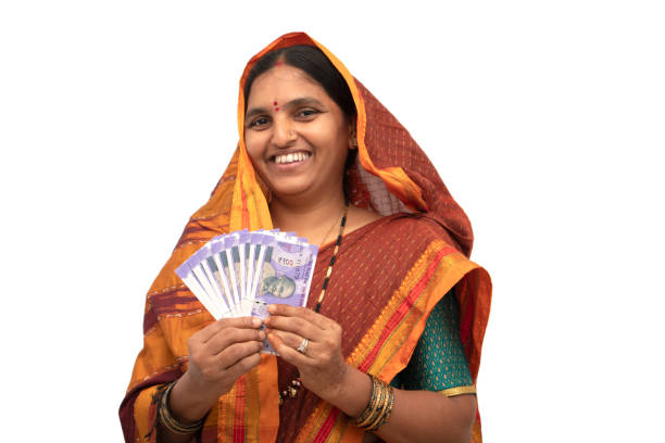 Happy smiling Indian woman holding Indian money or currency notes on isolated background - concept of woman empowerment, earnings, bank loan and business Happy smiling Indian woman holding Indian money or currency notes on isolated background - concept of woman empowerment, earnings, bank loan and business. loan india stock pictures, royalty-free photos & images