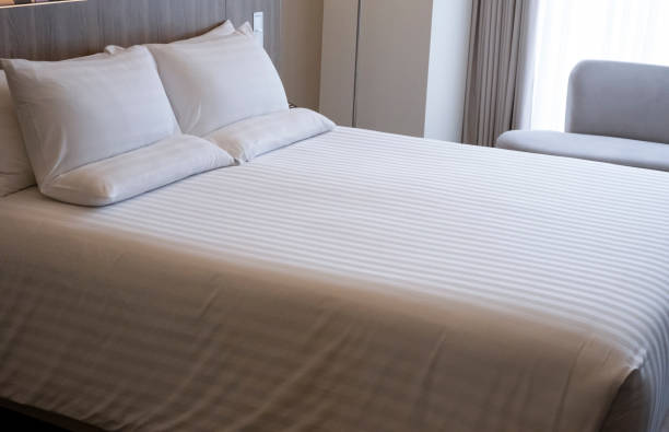 istock Clean white bed in hotel. White comfortable pillow on bed in bedroom. Bed sheets and pillows. Large bedroom, hotel room with white sheets, large pillows cushions. 1311115366