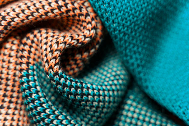 A pile of multi-colored synthetic knitted fabrics of different structures and textures. A stack of colorful fabrics smooth shapes background. Multicolored knitwear fabric