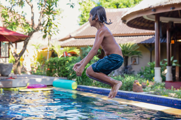 istock Mixed-Race Boy Jumping Into the Swimming Pool 1311117062