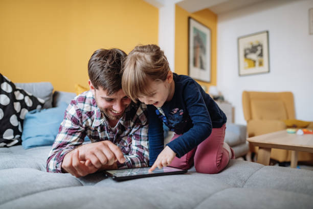 istock Millennial father and daughter playing online games on digital tablet 1311117123