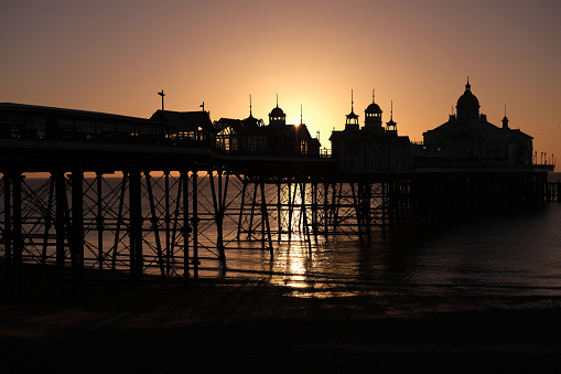 Clear skies and rising sun behind the pier in Eastbourne, East Sussex