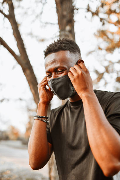 istock African Male Setting Up Headphones While Walking Outside With Face Mask 1311119501
