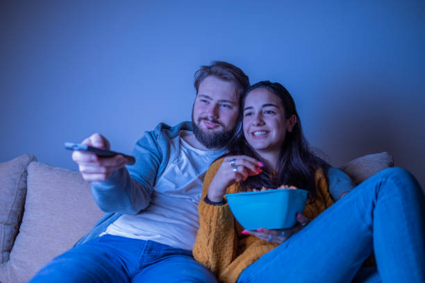 istock Young couple watching television and smiling 1311119593