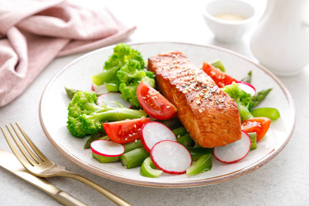 サーモンフィッシュフィレグリルと野菜サラダ、大根、トマト、ピーマン、ブロッコリー、アスパラガス。 - cooked pepper salmon food ストックフォトと画像
