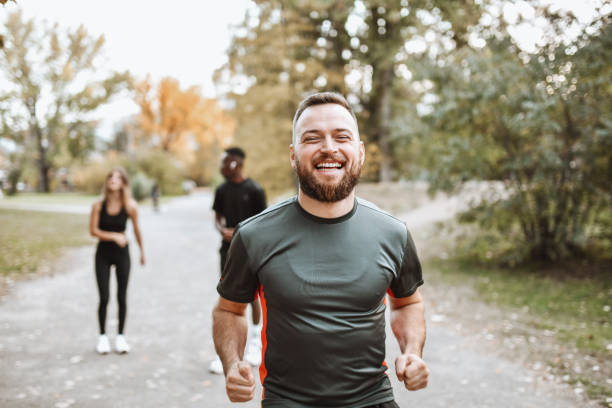 macho sorridente correndo no parque com amigos - couple stretching running jogging - fotografias e filmes do acervo