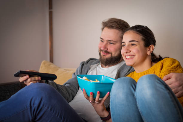 istock Young attractive pair eating popcorn and watching television 1311120971