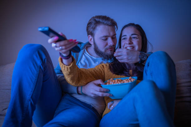istock Young couple eating popcorn and watching television 1311122059