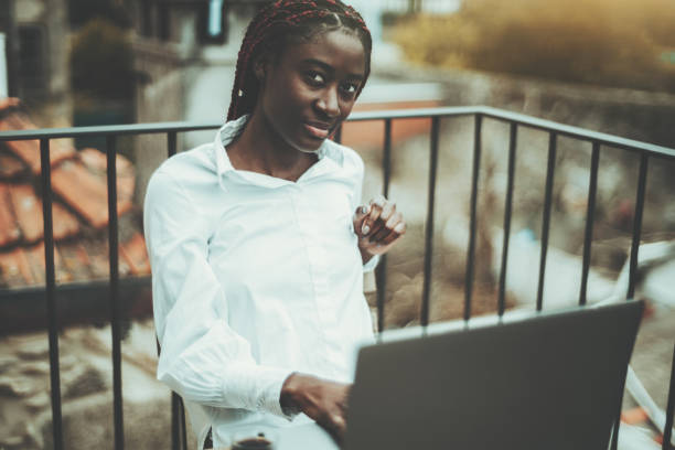 バルコニーでラップトップを使用して黒い女の子 - braids african descent women pensive ストックフォトと画像