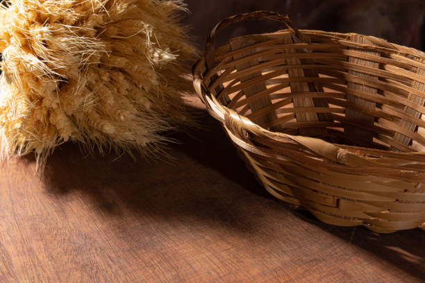 istock Empty straw basket and branch of wheat over wooden surface, selective focus. 1311122799