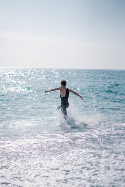 istock Young man runs down beach, into sea in the morning 1311122903